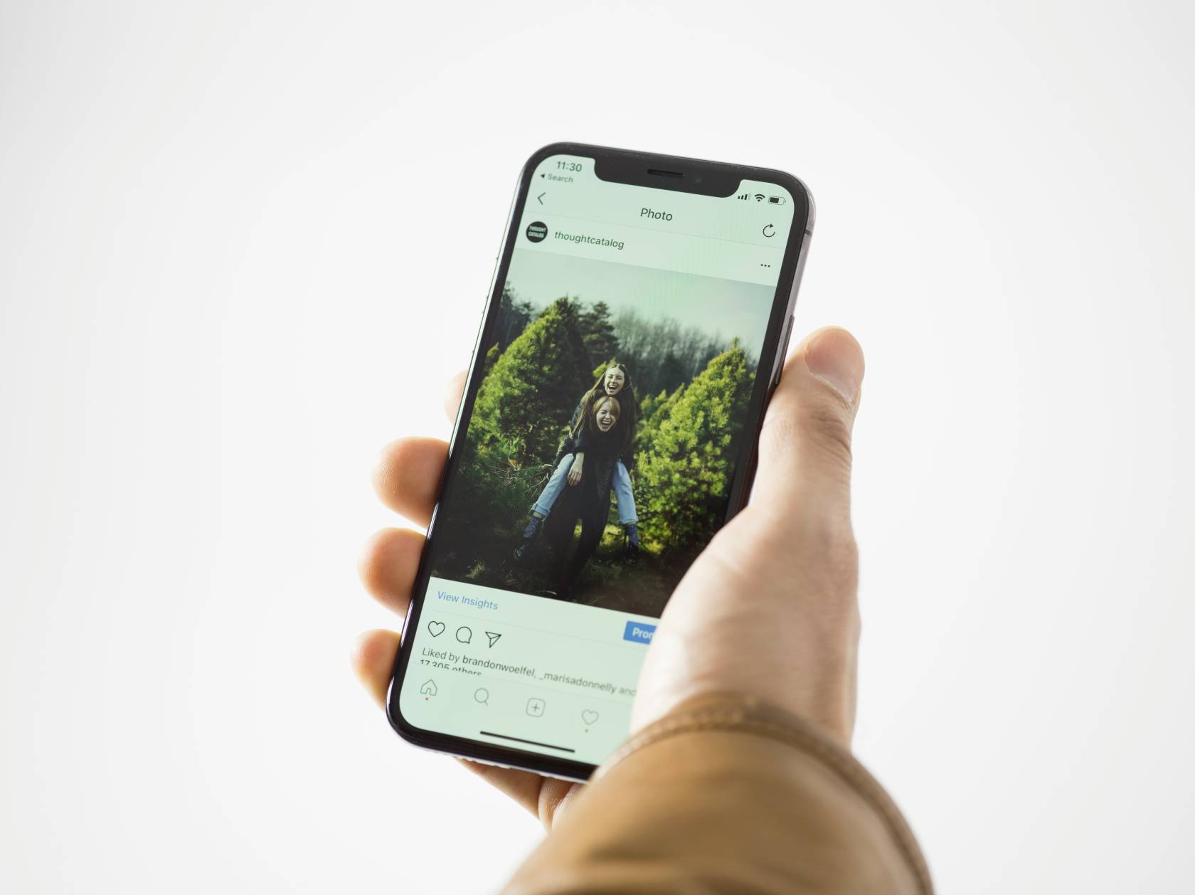 Person holding a mobile phone displaying the time as 11:30 on the screen while browsing Instagram.